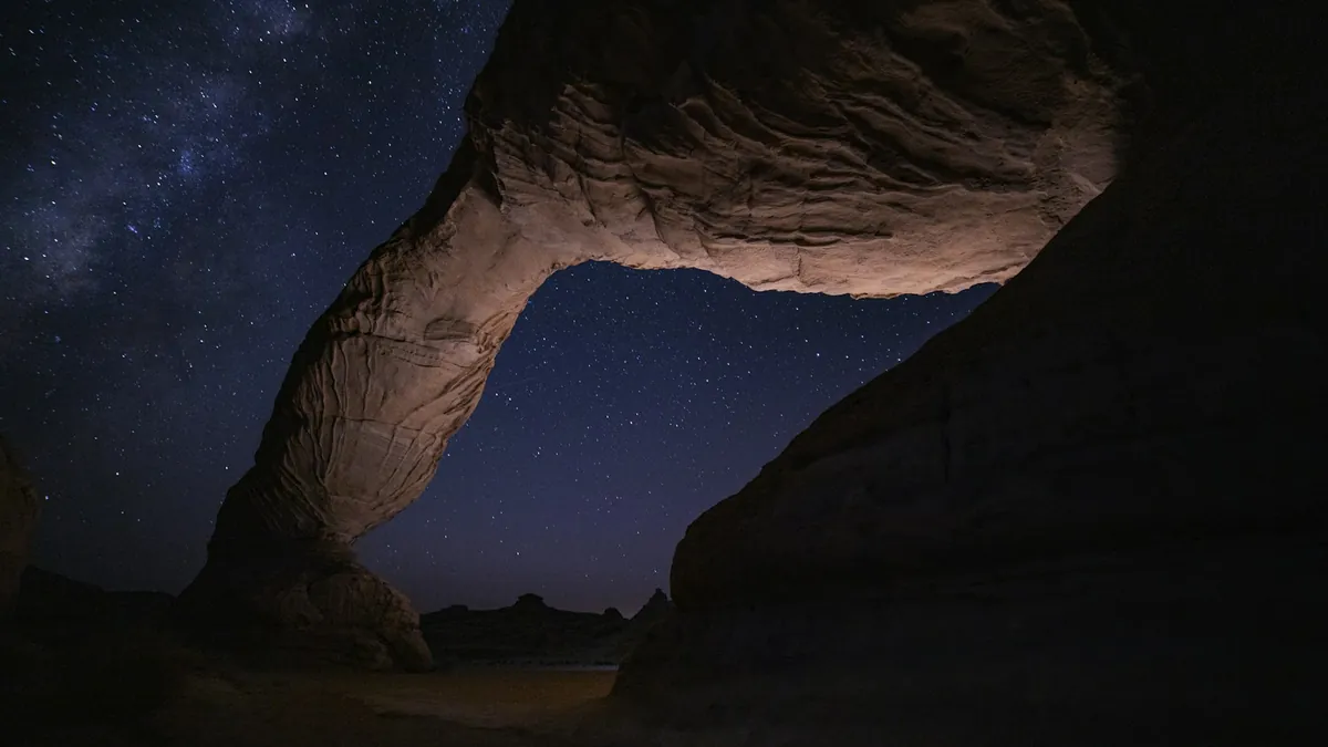 Rock arch under a starry night sky in AlUla